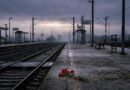 Şafak vakti ıssız bir tren garı peronu, rayların üzerinde bırakılmış tek bir demet karanfil